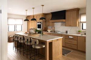 Remodeled kitchen with a large island, warm cabinetry, and black and gold accents.