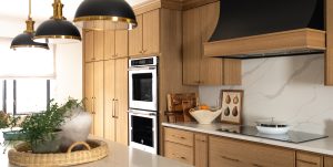 Close up of a remodeled kitchen with a large island, warm cabinetry, and black and gold accents.